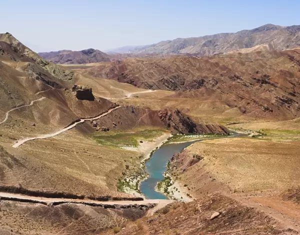 Hari Rud river flowing through fertile valley at base of red rock mountains