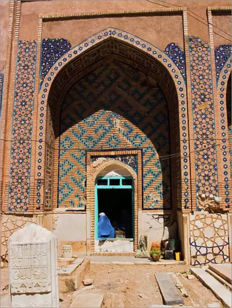 Lady pilgrim in blue burqa sitting in doorway at Sufi shrine of Gazargah