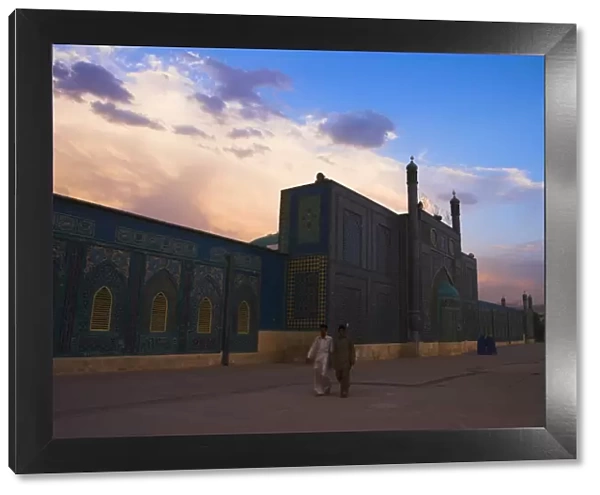 People walk at sunset past the Shrine of Hazrat Ali, who was assassinated in 661