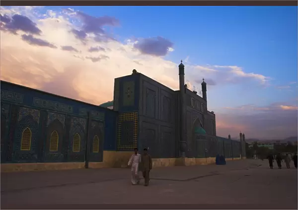 People walk at sunset past the Shrine of Hazrat Ali, who was assassinated in 661