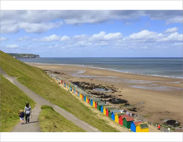 Elevated view of colourful beach huts on West Cliff Beach, mother and daughter hand in hand