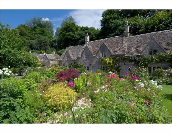 Traditional Cotswold stone cottages with colourful flower gardens, Bibury