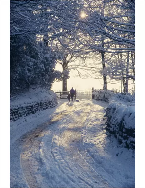 Man and child walking down a snow covered road in winter near Arthington