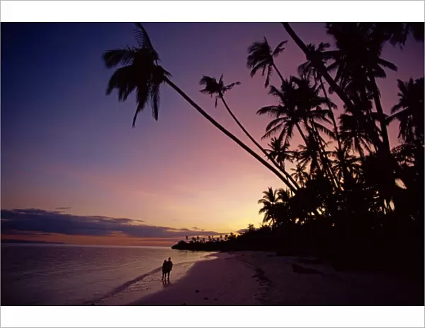 Couple and palm trees on Alona Beach silhouetted at