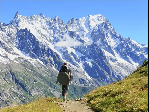 Hiker runs along trail with views on Grandes Jorasses and the Giant Tooth, Veny Valley