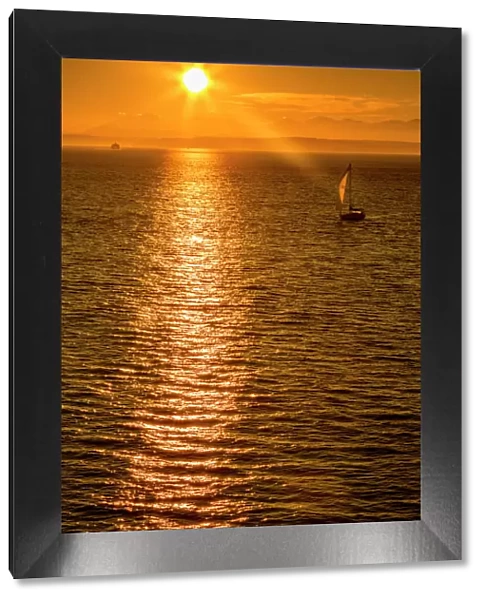 Sailing boat and sunset over Elliott Bay with Bainbridge Island visible on the horizon
