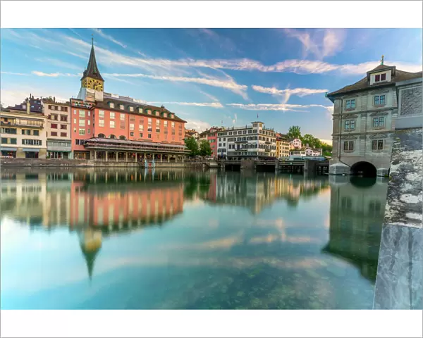 St. Peter church and old buildings of Lindenhof mirrored in Limmat River at dawn, Zurich