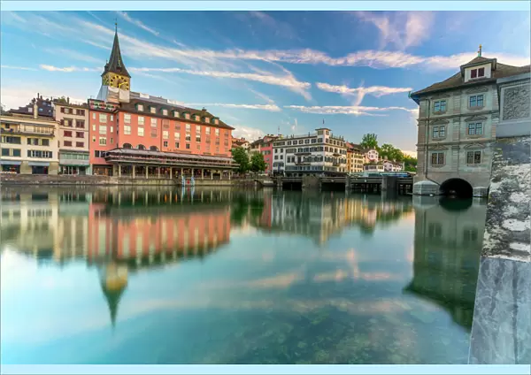 St. Peter church and old buildings of Lindenhof mirrored in Limmat River at dawn, Zurich