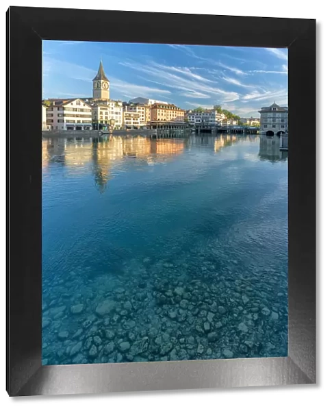 Clock tower of St. Peter church mirrored in the turquoise water of Limmat River, Lindenhof