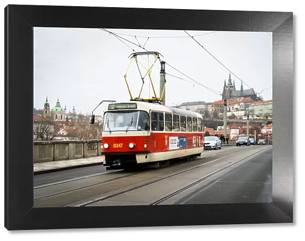 A traditional red tram crosses Manesuv most (bridge) with St