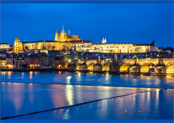 St. Vitus Cathedral and Prague Castle lit up during the evening blue hour reflecting