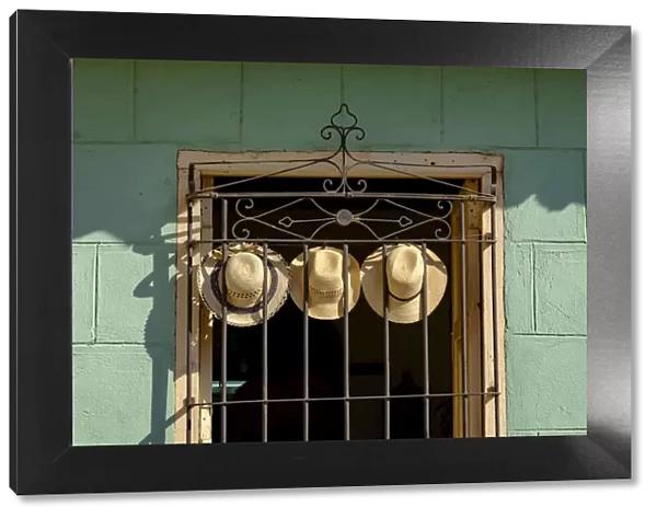 Three straw hats hang on an iron grate in a window, Trinidad, Cuba, West Indies