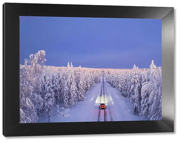 Overhead view of a car driving on empty, icy and slippery road with illuminated headlamps, Akaslompolo, Kolari, Pallas-Yllastunturi National Park, Lapland region, Finland, Europe