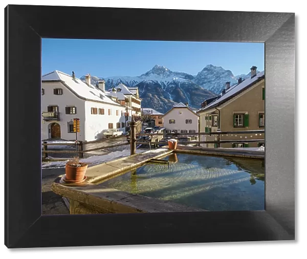 A plaza and fountain in the Alpine village of Sent in winter, Sent, Switzerland, Europe