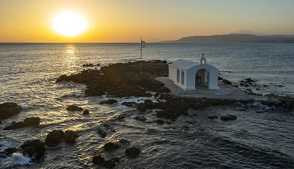 Aerial view of the small church of Agios Nikolaos on islet by the rough sea at sunrise, Georgioupolis, Crete island, Greek Islands, Greece, Europe