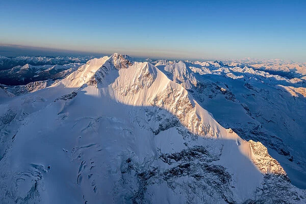 Aerial view of the snow covered Piz Bernina and Biancograt mountains at dawn, Engadine