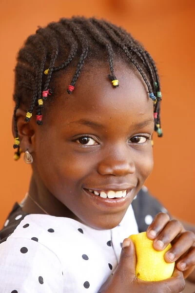 African girl eating an orange, Lome, Togo, West Africa, Africa