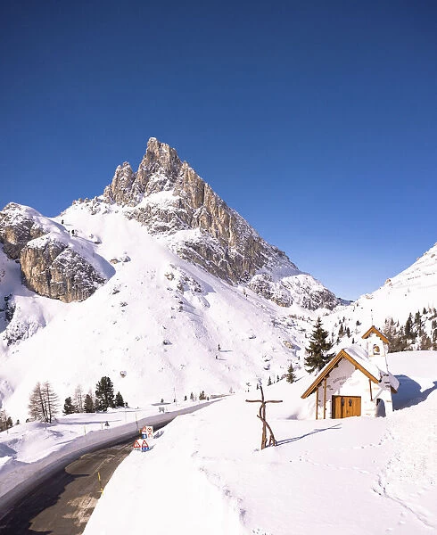Alpine chapel in the snowy landscape with Sass de Stria peak in the background
