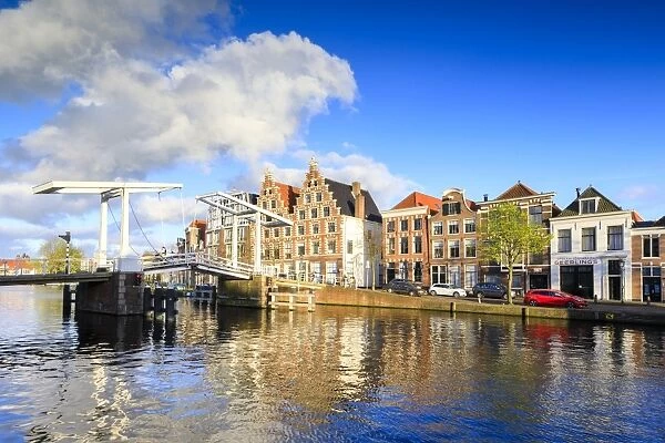 Blue sky and clouds on typical houses reflected in the canal of the River Spaarne