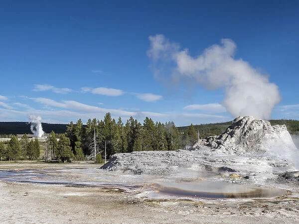 Castle Geyser steaming, with Old Faithful erupting behind, in Yellowstone National Park