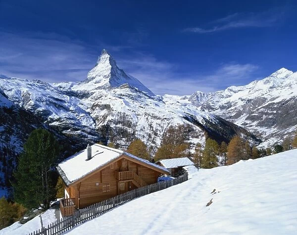 Chalets in a snowy landscape with the Matterhorn peak, near Zermatt, Swiss Alps