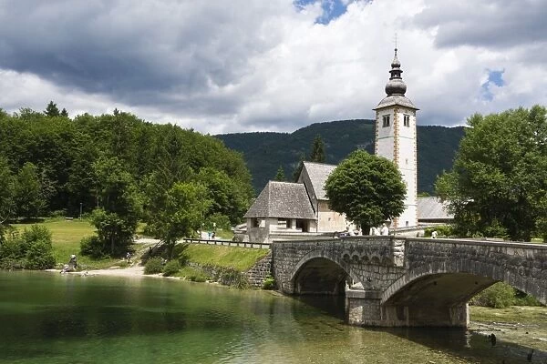 The church of St. John the Baptist and the stone bridge on Lake Bohinj, Slovenia, Europe