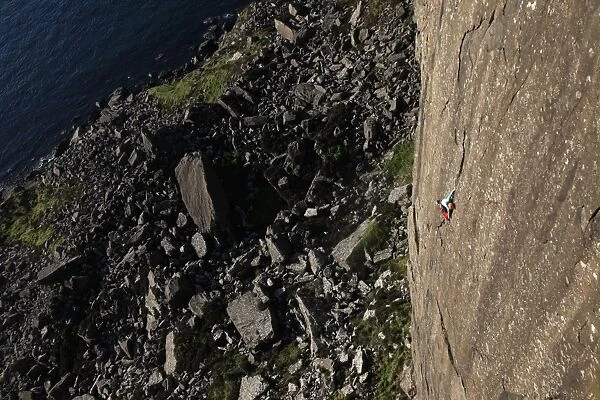 A climber scales the 100 metre cliffs at Fair Head, County Antrim, Ulster, Northern Ireland