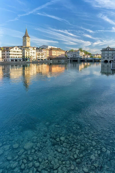 Clock tower of St. Peter church mirrored in the turquoise water of Limmat River, Lindenhof