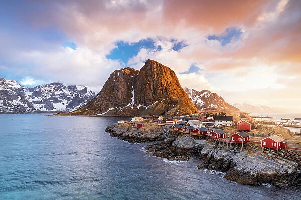 Clouds at sunrise over traditional Rorbu cottages on cliffs by the cold arctic sea, Hamnoy, Reine, Lofoten Islands, Norway, Europe