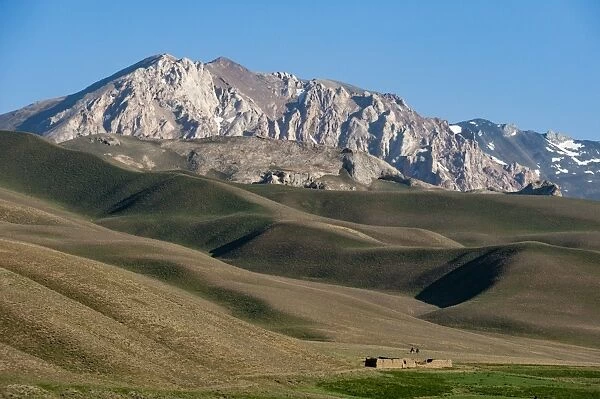 A distant house in the grasslands with views of mountains in the distance, Bamiyan province