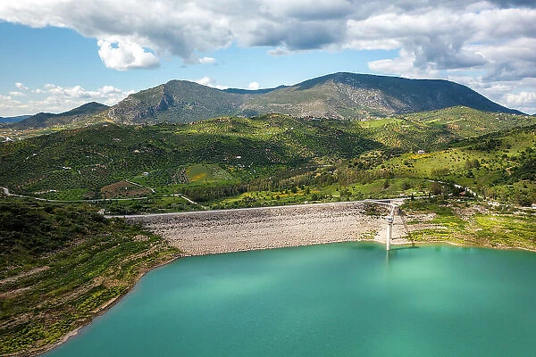 Drone aerial view of Zahara de la Sierra water reservoir dam with turquoise water and mountains in the background, Andalusia, Spain, Europe