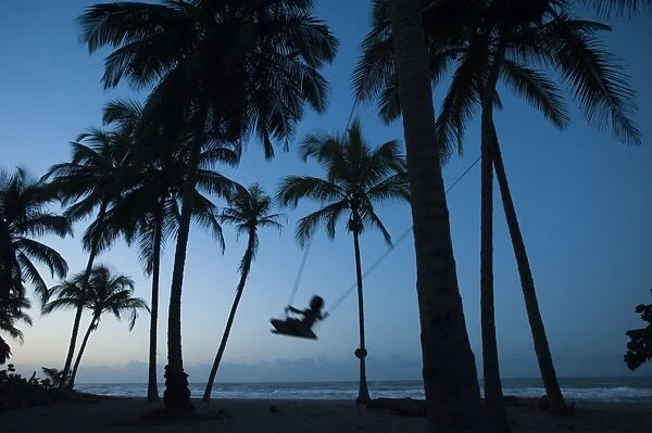 A girl plays on a swing tied between palm trees on the Carribean coast at Palomino in Colombia