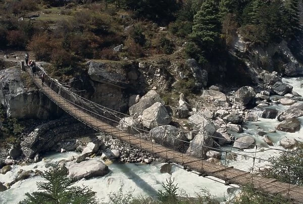 High angle view of trekkers crossing rope bridge over