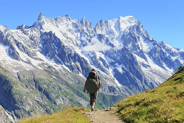 Hiker runs along trail with views on Grandes Jorasses and the Giant Tooth, Veny Valley