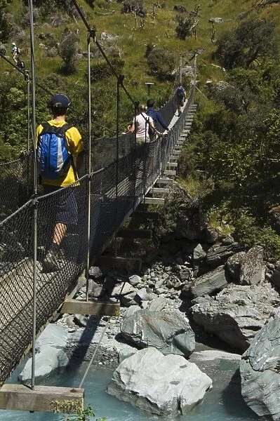 Hikers crossing a suspension bridge on Rob Roy Glacier Hiking Track