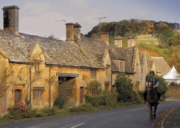 Horse and rider passing honey coloured stone cottages in the village of Stanton