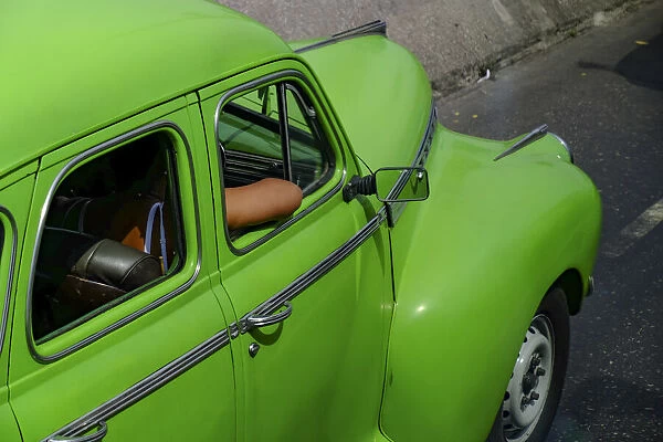 Lime green vintage car with passengers arm through window, Havana, Cuba, West Indies