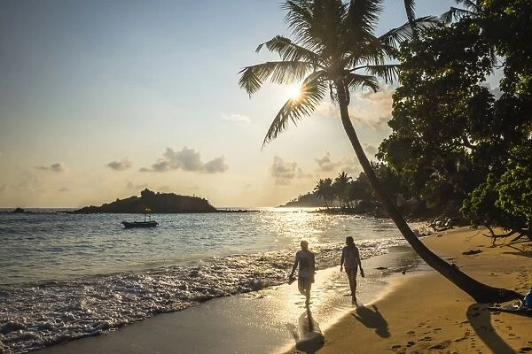 Mirissa Beach, couple taking a romantic walk under a palm tree at sunset, South Coast, Sri Lanka, Asia