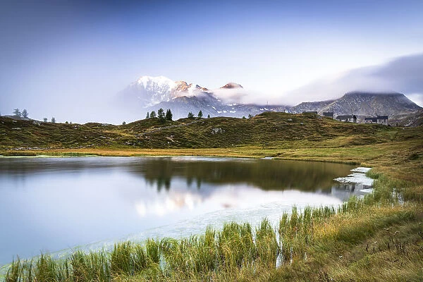 Mist on Fletschhorn and Galehorn mountains reflected in Hopschusee lake at dawn