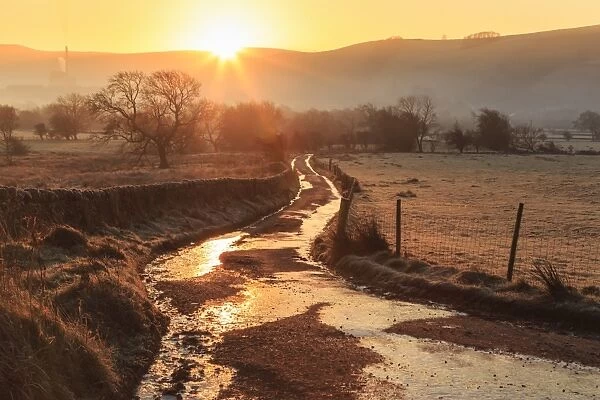 Misty and frosty sunrise over a country lane in winter, Castleton, Peak District National Park