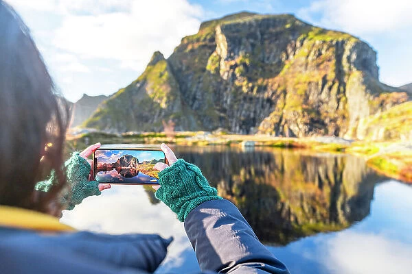 Personal perspective of woman photographing mountains in autumn with smartphone, A i Lofoten, Moskenes, Lofoten Islands, Nordland, Norway, Scandinavia, Europe
