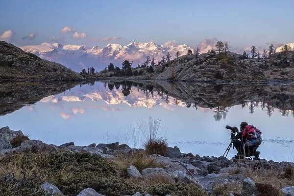 A photographer contemplating the sunset over the Monte Rosa from the Lake Bianco in the Mont Avic Natural Park, Aosta Valley, Italy, Europe
