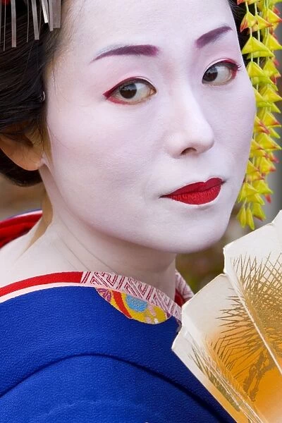 Portrait of a geisha holding a traditional paper fan