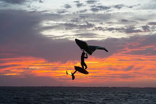 Pro surfer James Jenkins jumps his wing surfer at sunset over the Pamlico Sound at Nags
