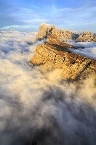 The profiles of the pinnacles of the Geisler Group in the Dolomites emerging from the fog at sunset, South Tyrol, Italy, Europe