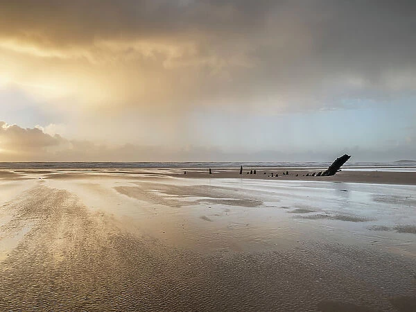 Rain sweeping across Rhossili at sunset showing the shipwreck of the Helvetia, Rhossili, Gower, South Wales, United Kingdom, Europe