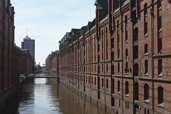 Red brick warehouses overlook a canal in the Speicherstadt district, once a duty free port, in Hamburg, Germany, Europe