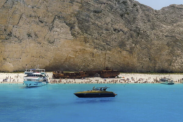 Shipwreck on Navagio Beach, a famous beach with crystal clear waters, moored leisure boats and bathers, Zakynthos, Ionian Islands, Greek Islands, Greece, Europe