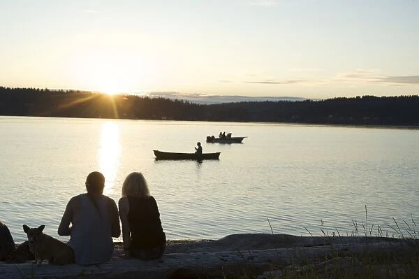 Silhouette of couple with dog watching sunset at Lisabeula Beach, Vashon Island