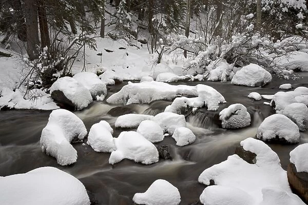 Snow-covered boulders and flowing creek